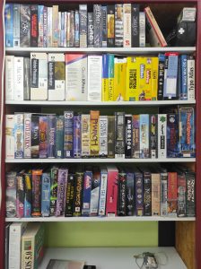Ein Regal mit vielen original Softwareschachteln - 3 Fächer mit Spielen aus den 90ern und frühen 2000ern, dazwischen ain Fach mit Macintosh-Software (z.B. Photoshop oder QuarkXPress).