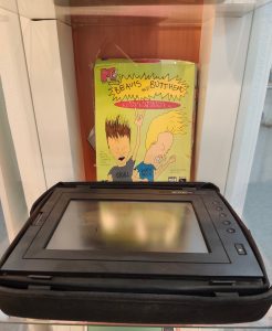 In einer Vitrine steht hinter einem Gridpad Tablettrechner von 1990 steht eine gelbe Schachtel mit der Aufschrift "MTV's Beavis and Butt-Head Multimeda Screen Saver". Darunter sind die Zeichnungen der beiden Figuren zu sehen. Daneben stehen Sprechtexte für Butt-Head "Hey Beavis! This is gonna be cool. Huh Huh" und Beavis "Ya. We're cool Heh Heh".