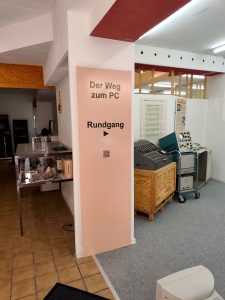 Ein Schild mit dem Text "Der Weg zum PC" sowie "Rundgang" und ein nach rechts in die Ausstellung weisender Pfeil